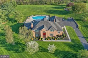 A sprawling mansion featuring a central pool, surrounded by the grand architecture of the house, offering luxury and relaxation